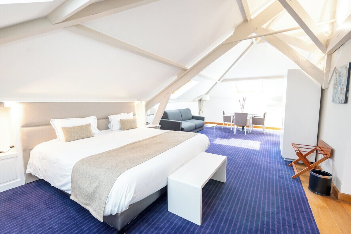 Un dormitorio moderno y espacioso con una cama grande, un área de descanso y vistas al exterior.