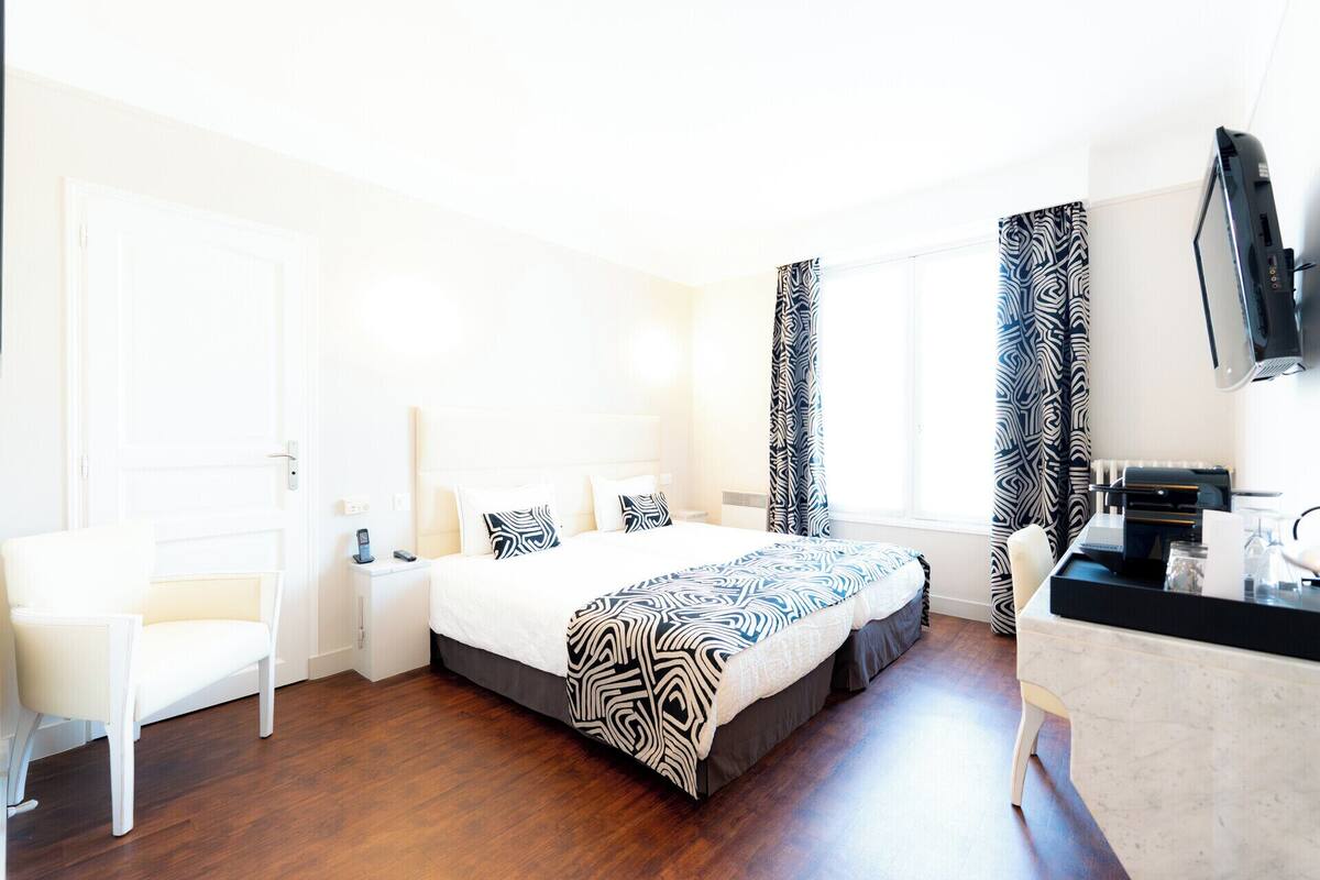Habitación de hotel con cama, escritorio, silla y televisión.