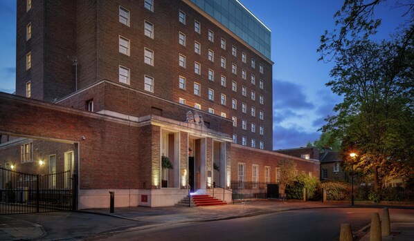 A multi-story hotel with a brick facade, large windows, and a modern entrance with steps.