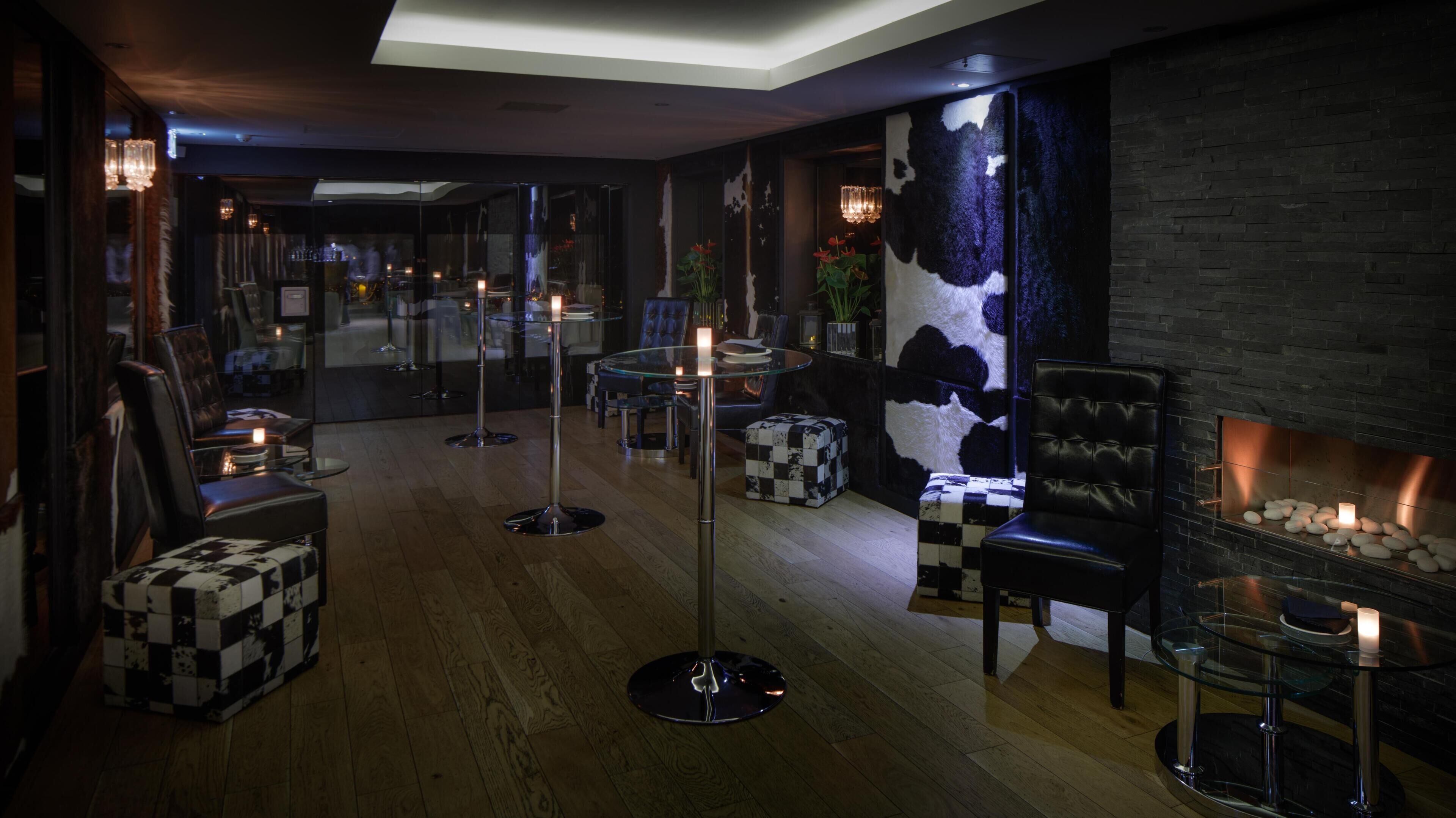 A modern lounge area with a fireplace, seating, and a bar.