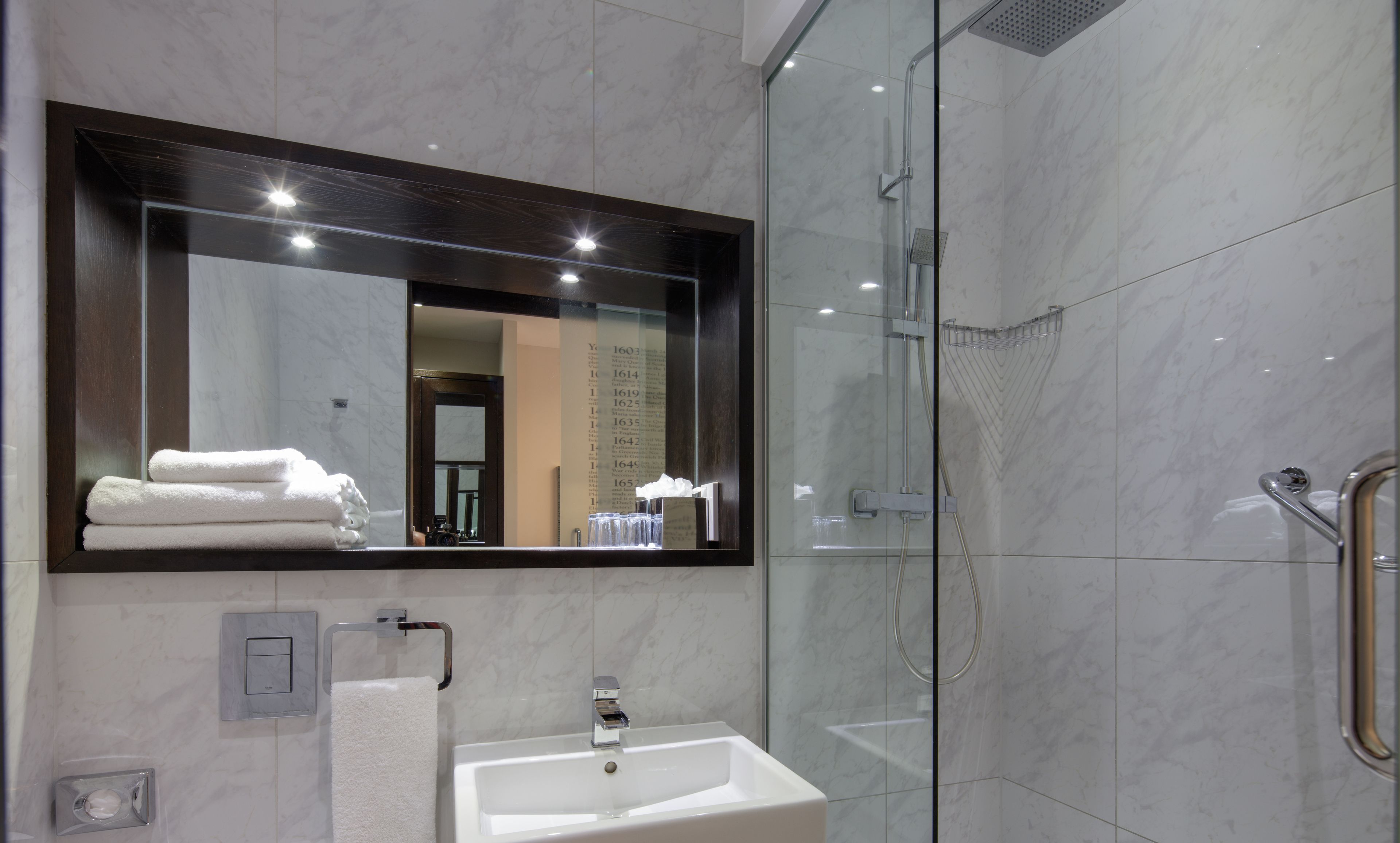 Une salle de bain moderne avec un grand miroir, un lavabo et une douche à parois de verre.