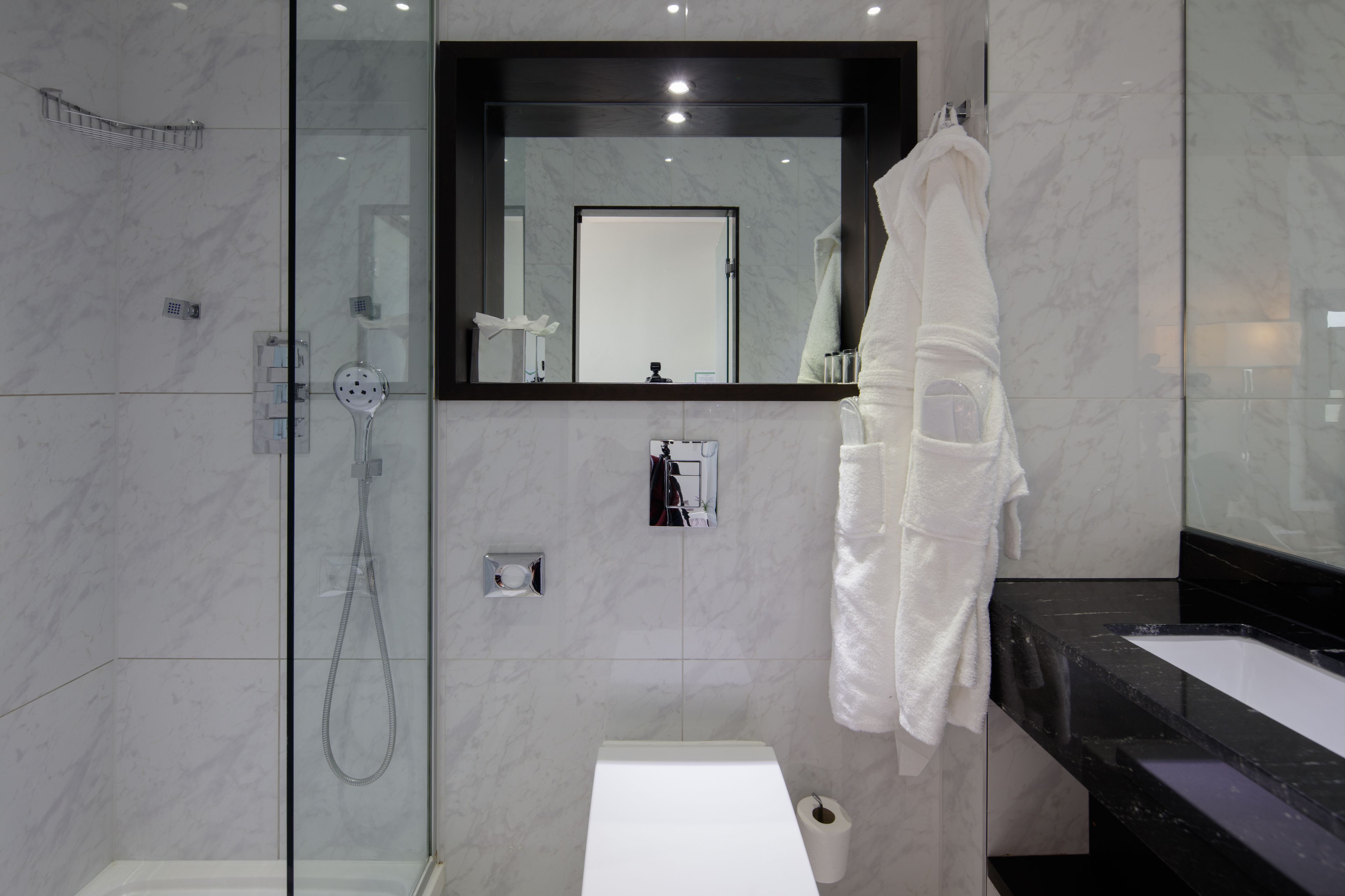 A modern bathroom with a glass-enclosed shower, a white sink, and a large mirror above the sink.
