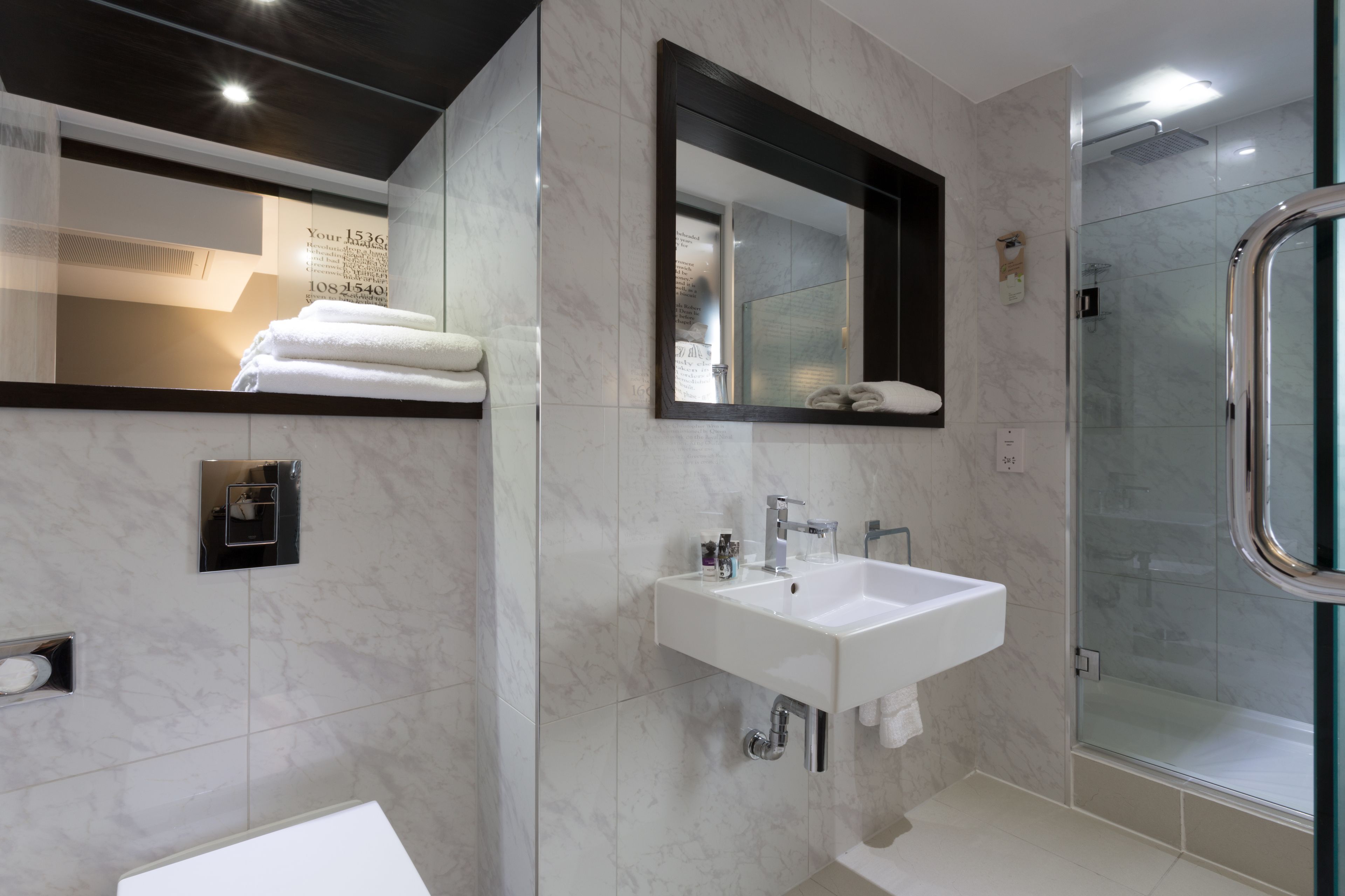 Une salle de bain moderne avec un lavabo blanc, un miroir et une cabine de douche en verre.