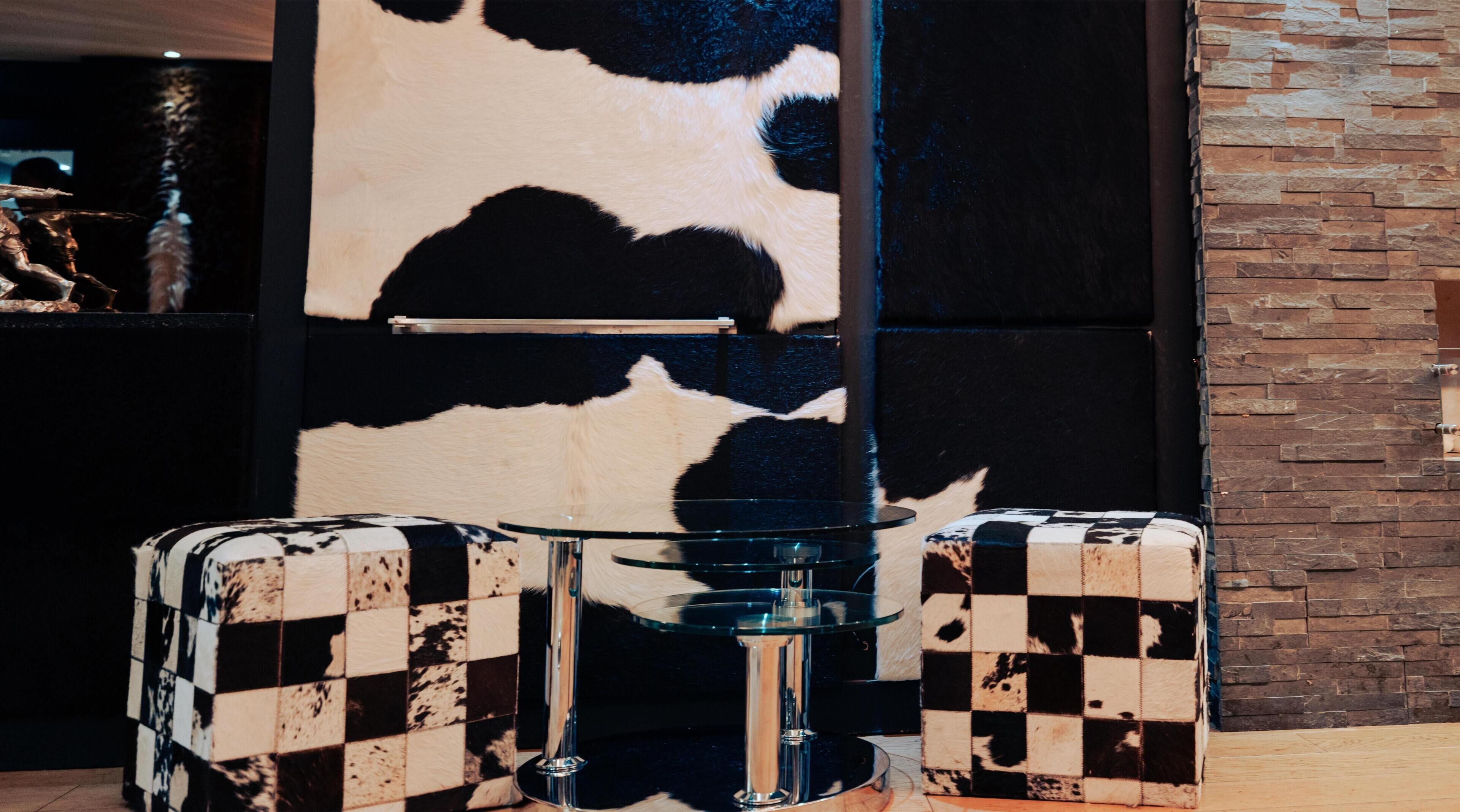 A checkered suitcase with a metallic base, a glass table, and a stone wall in the background.