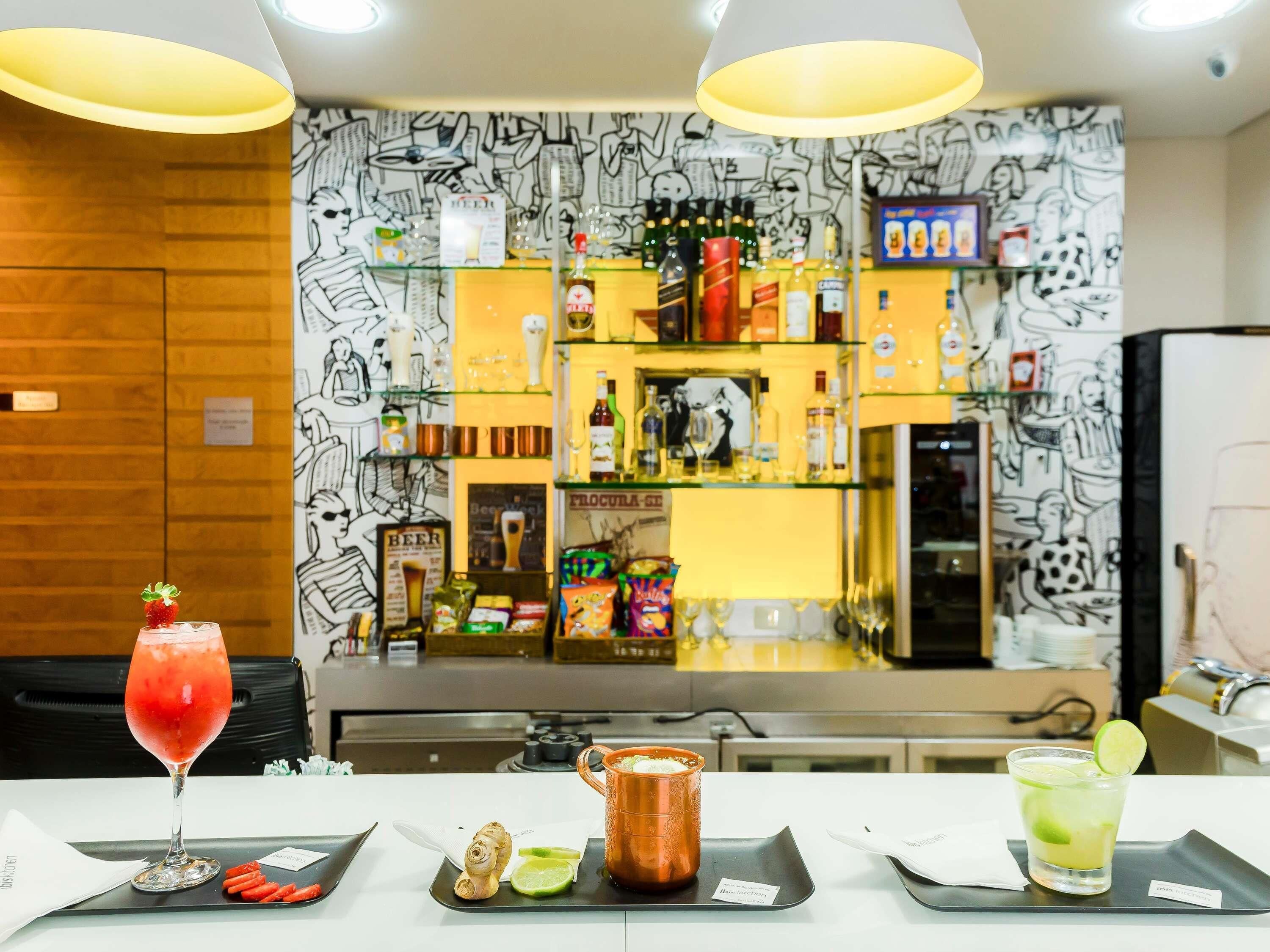 A bar area with a variety of bottles and glasses, a menu board, and a counter with a tray of food and drinks.