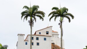 Un edificio blanco con techo de tejas rojas, rodeado de palmeras.