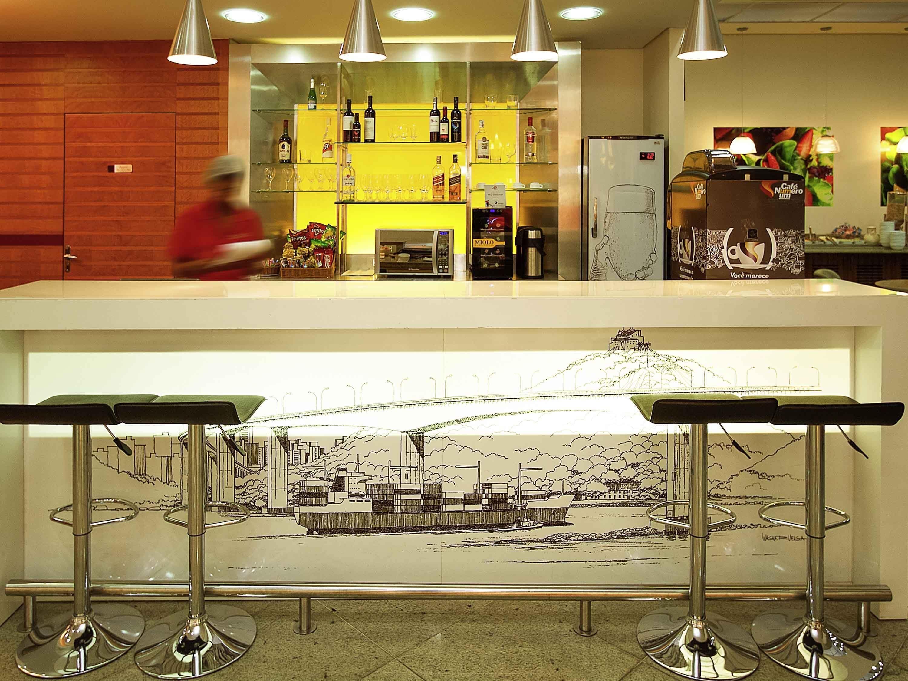 A bar area with a cityscape artwork, a coffee machine, and a refrigerator.