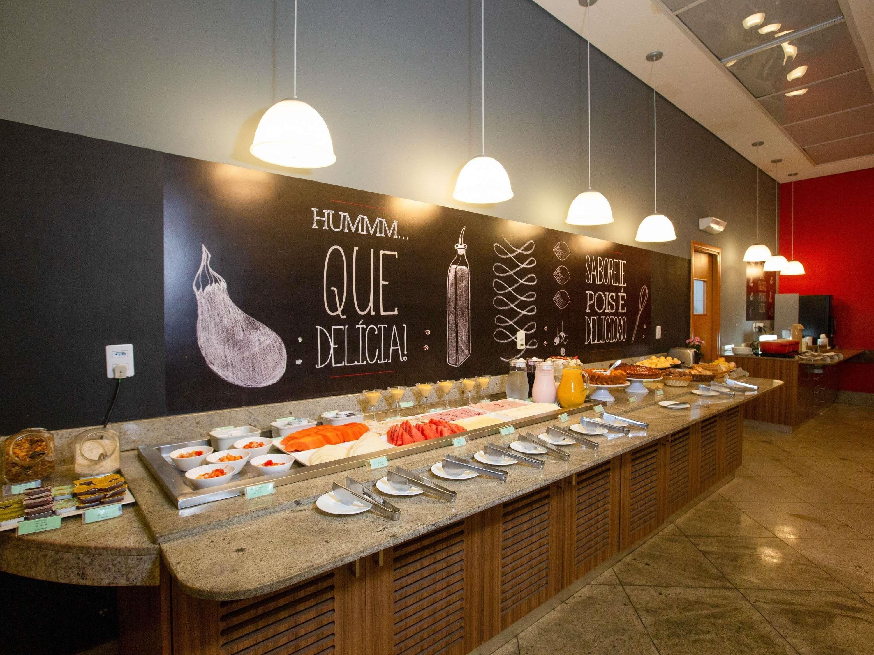 Buffet com diversos tipos de comida e uma parede com texto e ilustrações.
