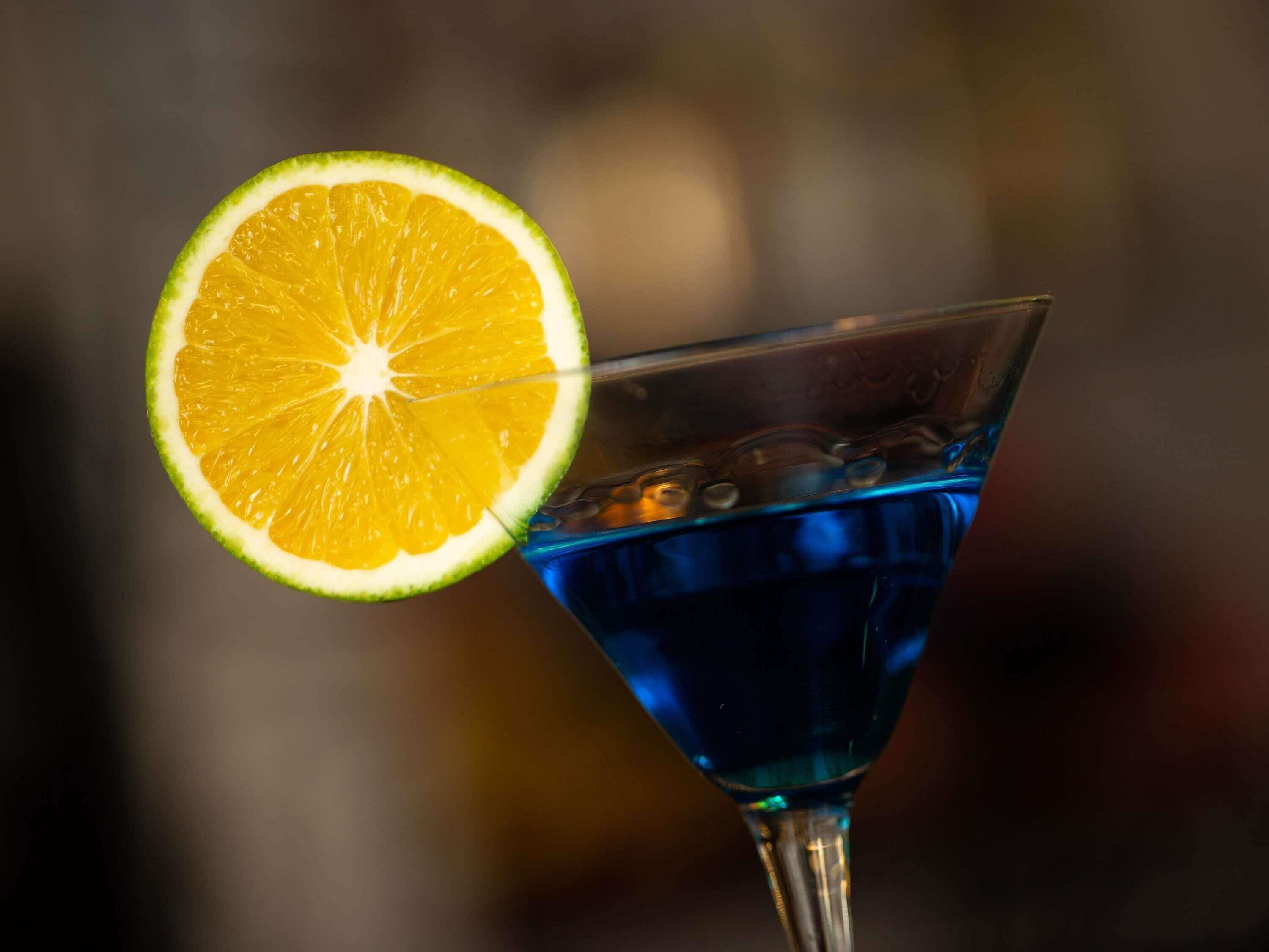 A martini glass with a slice of orange and ice cubes.