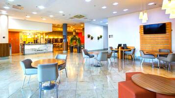 A spacious lobby with multiple seating areas, a reception desk, and a bar area.