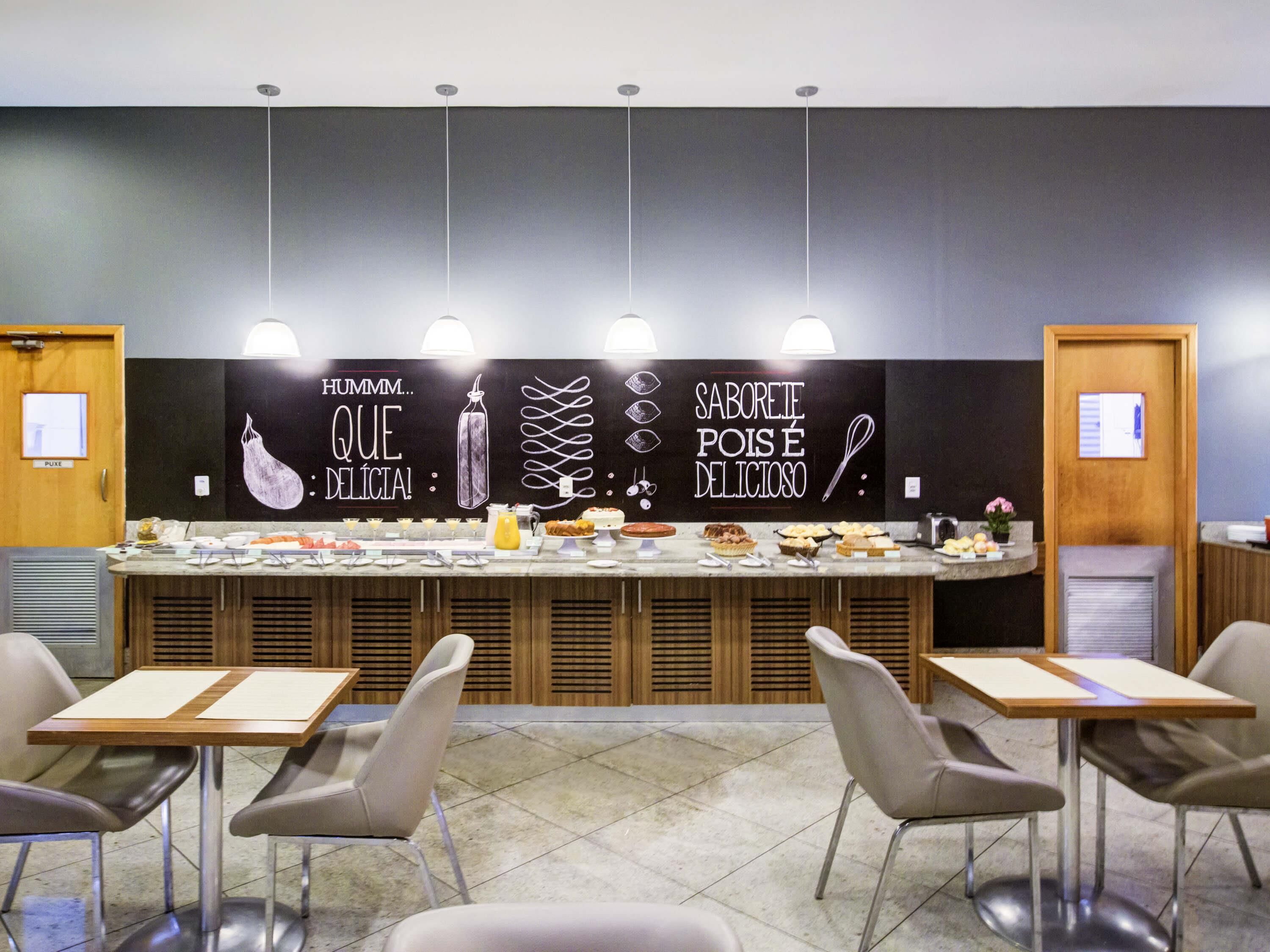 A buffet area with a variety of food items, a blackboard with text, and modern furniture.