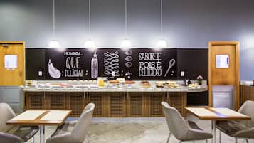 A buffet area with a variety of food items, a blackboard with text, and modern furniture.