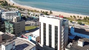 Un paisaje urbano costero con una playa, edificios modernos y un hotel de gran altura que destaca, con vistas al mar.
