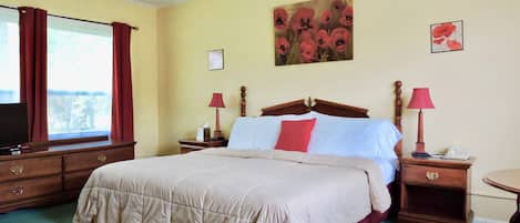 Quarto de hotel com uma cama grande, duas mesas de cabeceira com luminárias, uma TV e uma janela com cortinas.
