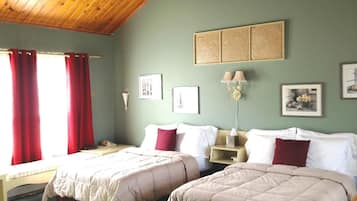 Una habitación con dos camas, techo de madera y pared verde decorada con cuadros.