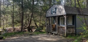 A small cabin with a porch, surrounded by a forest. - Abrams Creek Center (Elk Garden)