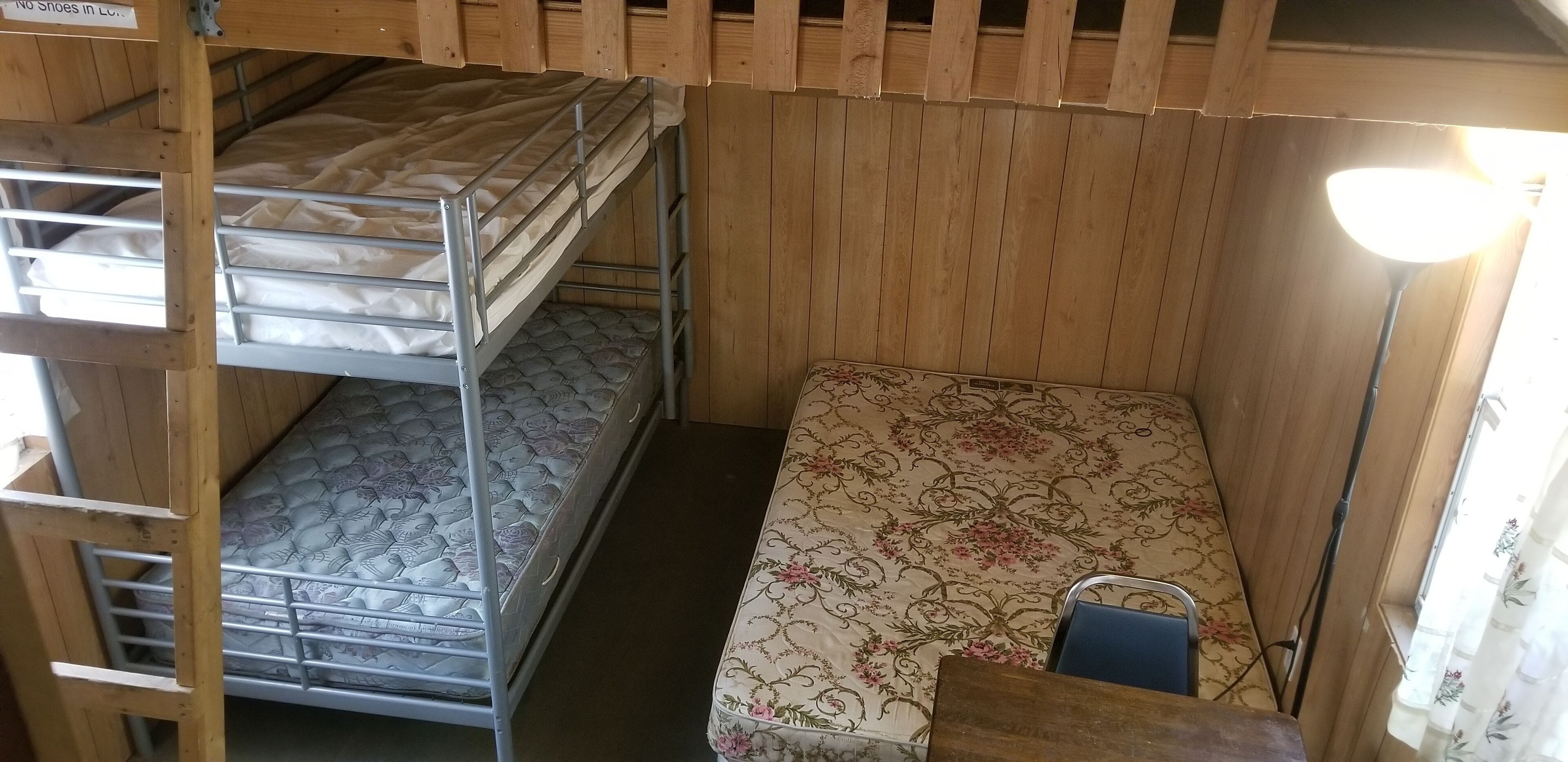Dormitorio con literas, techo de madera y una cama individual con colcha estampada.
