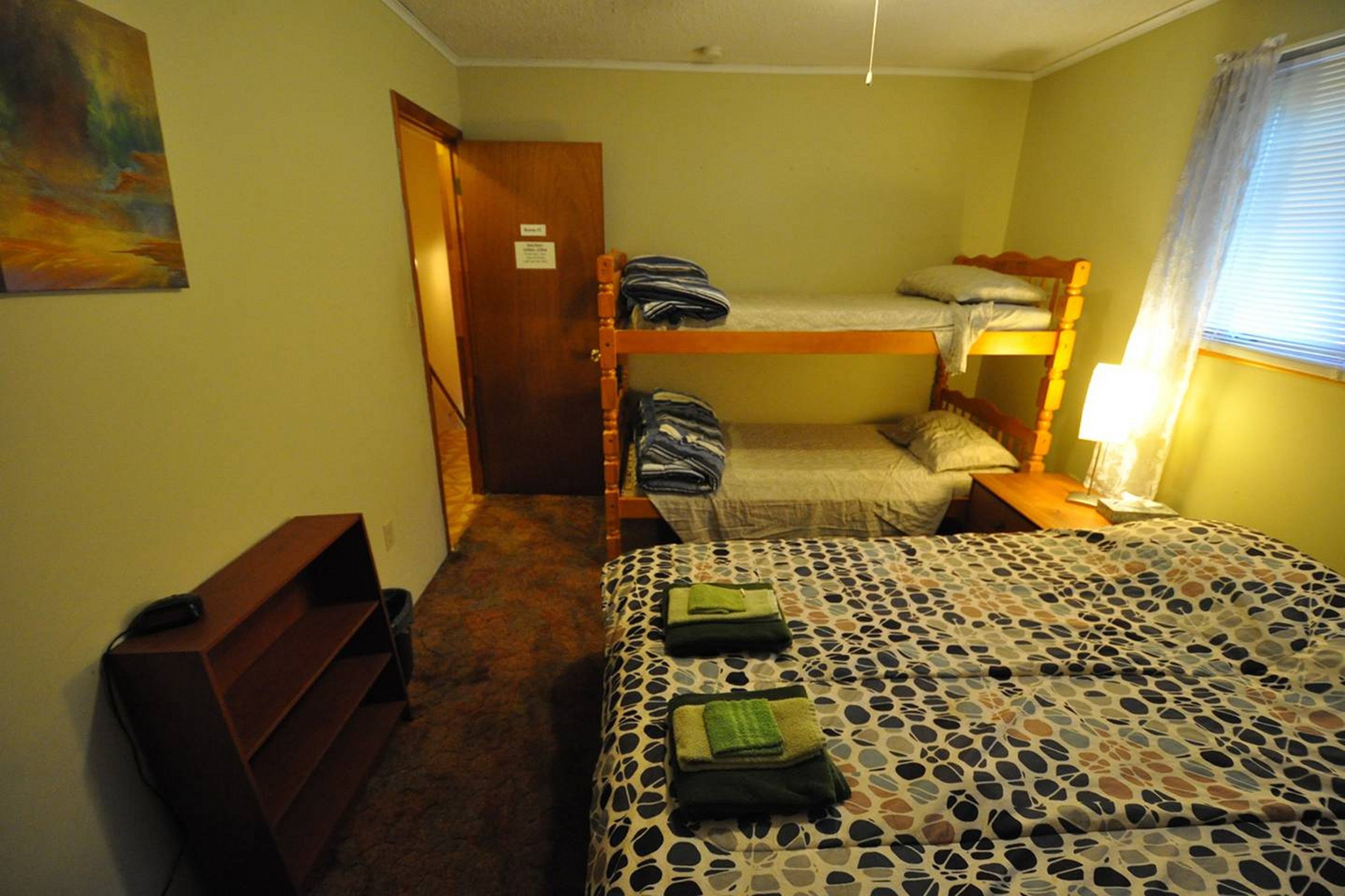 Una habitación con literas, un escritorio, una silla y una cama con colcha estampada.