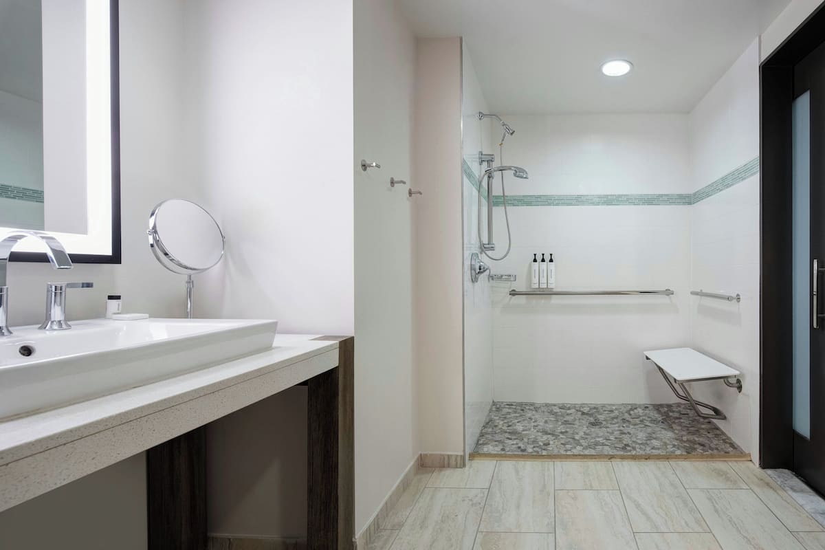 A modern bathroom with a white sink, mirror, and shower area.