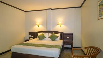Une chambre d’hôtel avec un grand lit, deux tables de chevet, une chaise et deux lampes fixées au mur.