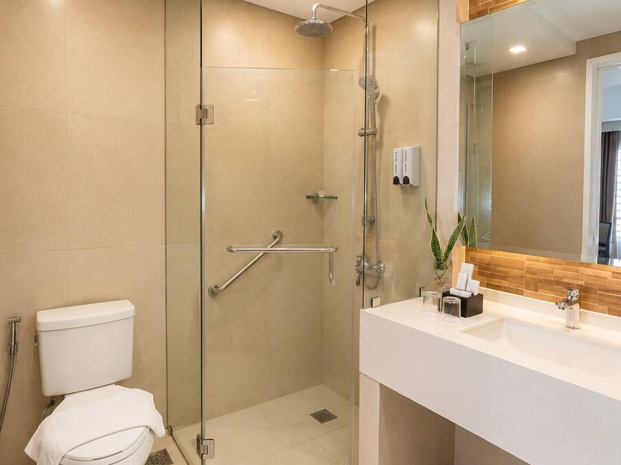 A modern bathroom with a glass-enclosed shower, a white toilet, and a vanity with a mirror.