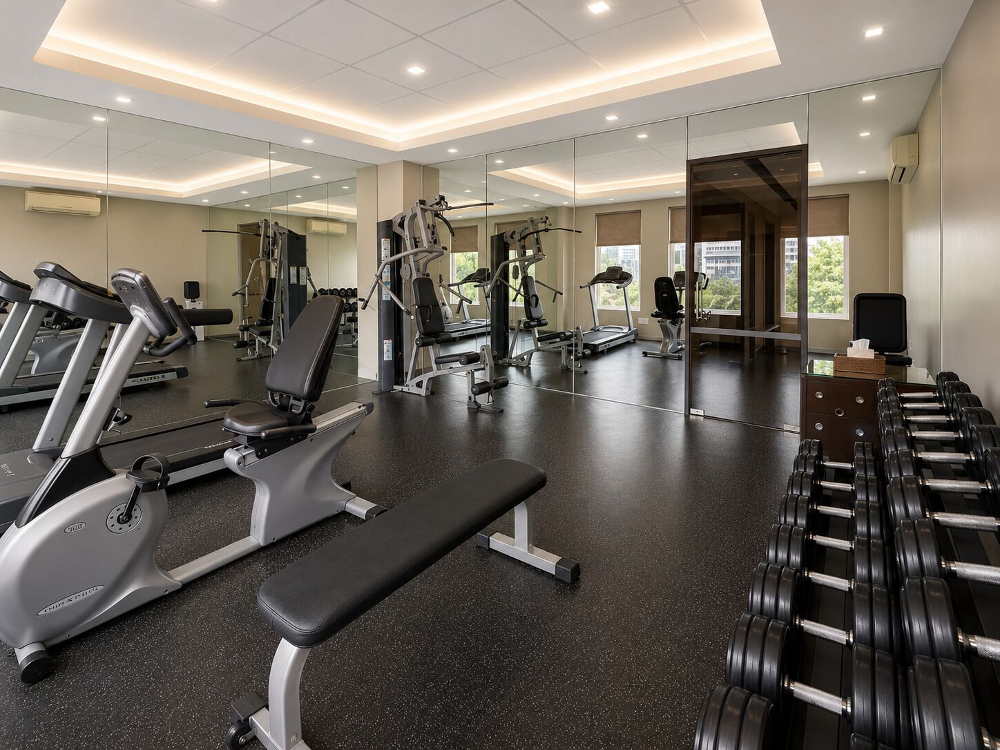 A gym with cardio machines, weight benches, and dumbbells.