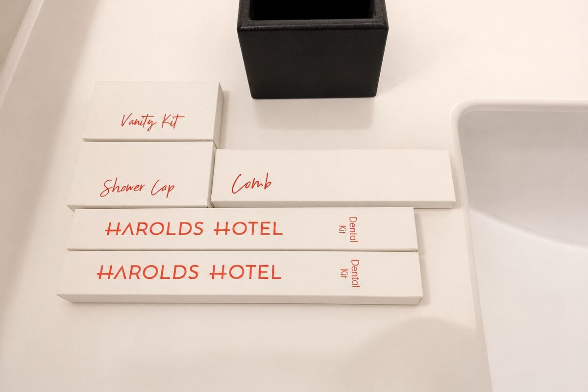 A hotel room with a white vanity kit, a shower cap, a comb, and a dental kit.