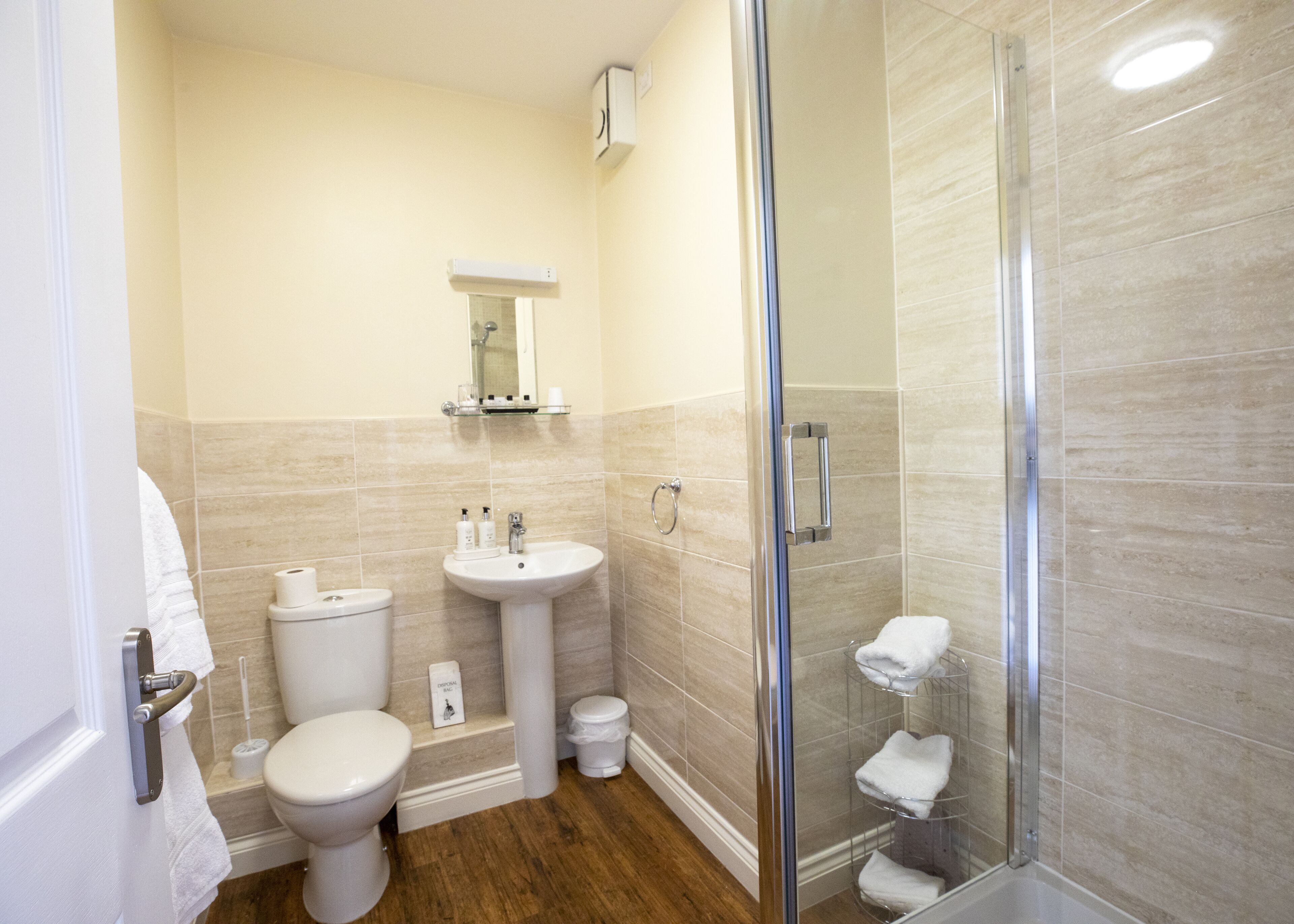 A modern bathroom with a toilet, sink, and glass shower enclosure.