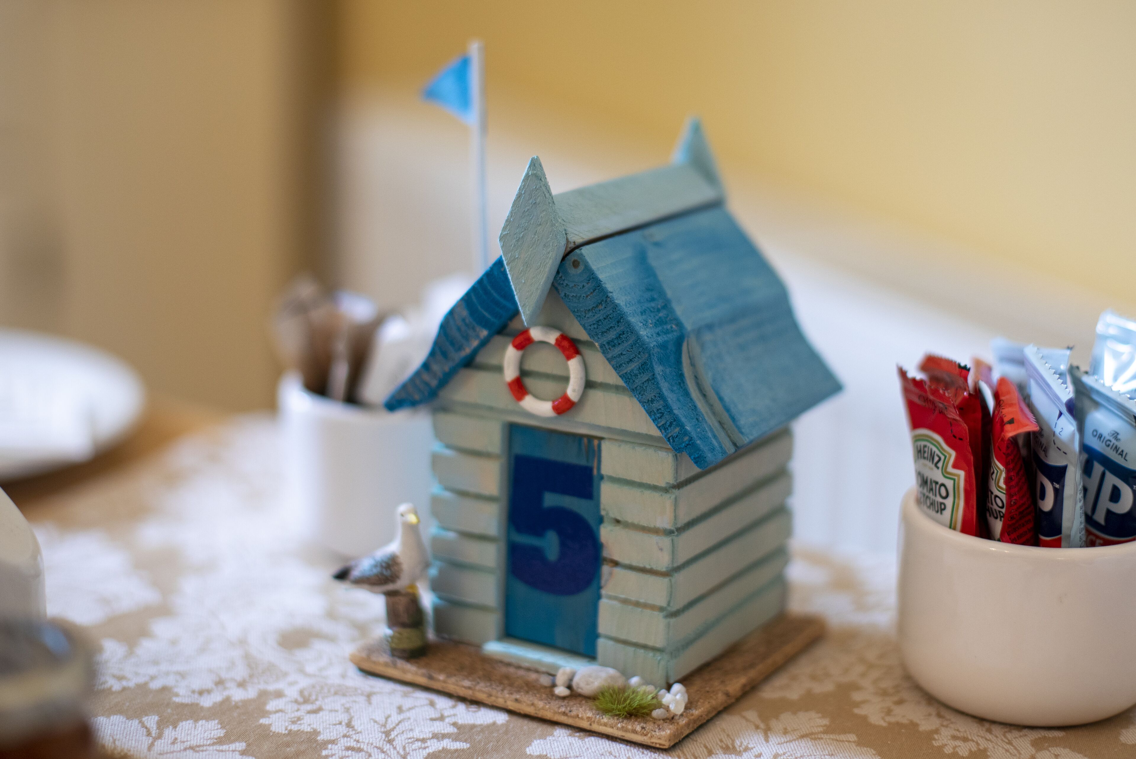 A small wooden house model with a flag, numbered 5, and a life ring on the roof.