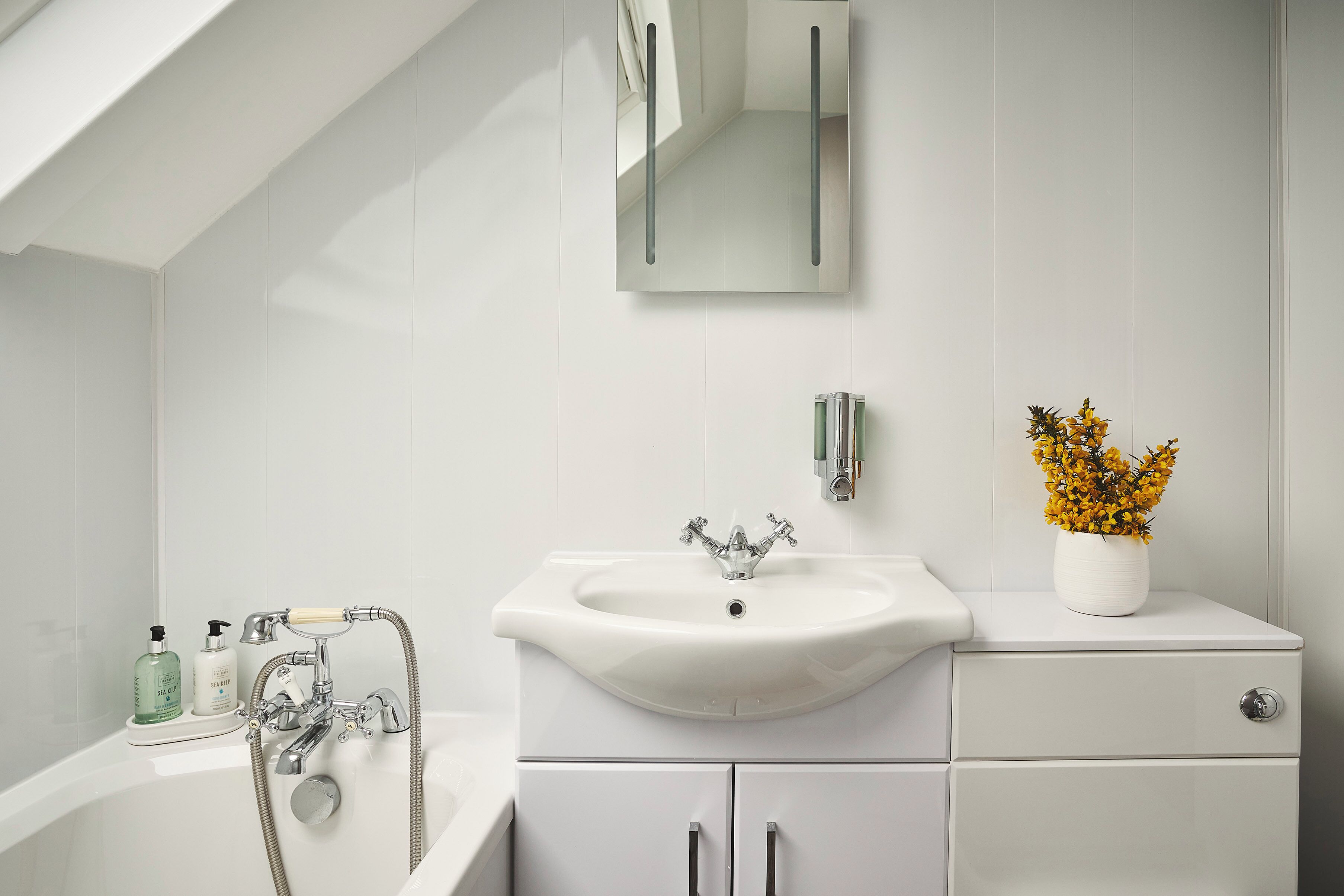 Un baño moderno con bañera, lavamanos y espejo.