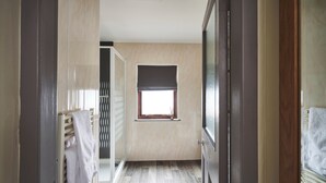 A narrow hallway with a radiator, a window with a blind, and a door leading to another room. - Inn at Port nan Gael (Isle of Mull)