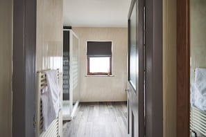 A narrow hallway with a radiator, a window with a blind, and a door leading to another room. - Inn at Port nan Gael (Isle of Mull)