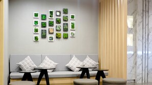 A seating area with a grey sofa, patterned cushions, and three round ottomans. - Krabi Royal Hotel (Krabi)