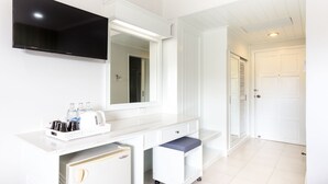 A modern bathroom with a white vanity, a mirror, a flat-screen TV, and a small cart with toiletries. - Krabi Royal Hotel (Krabi)