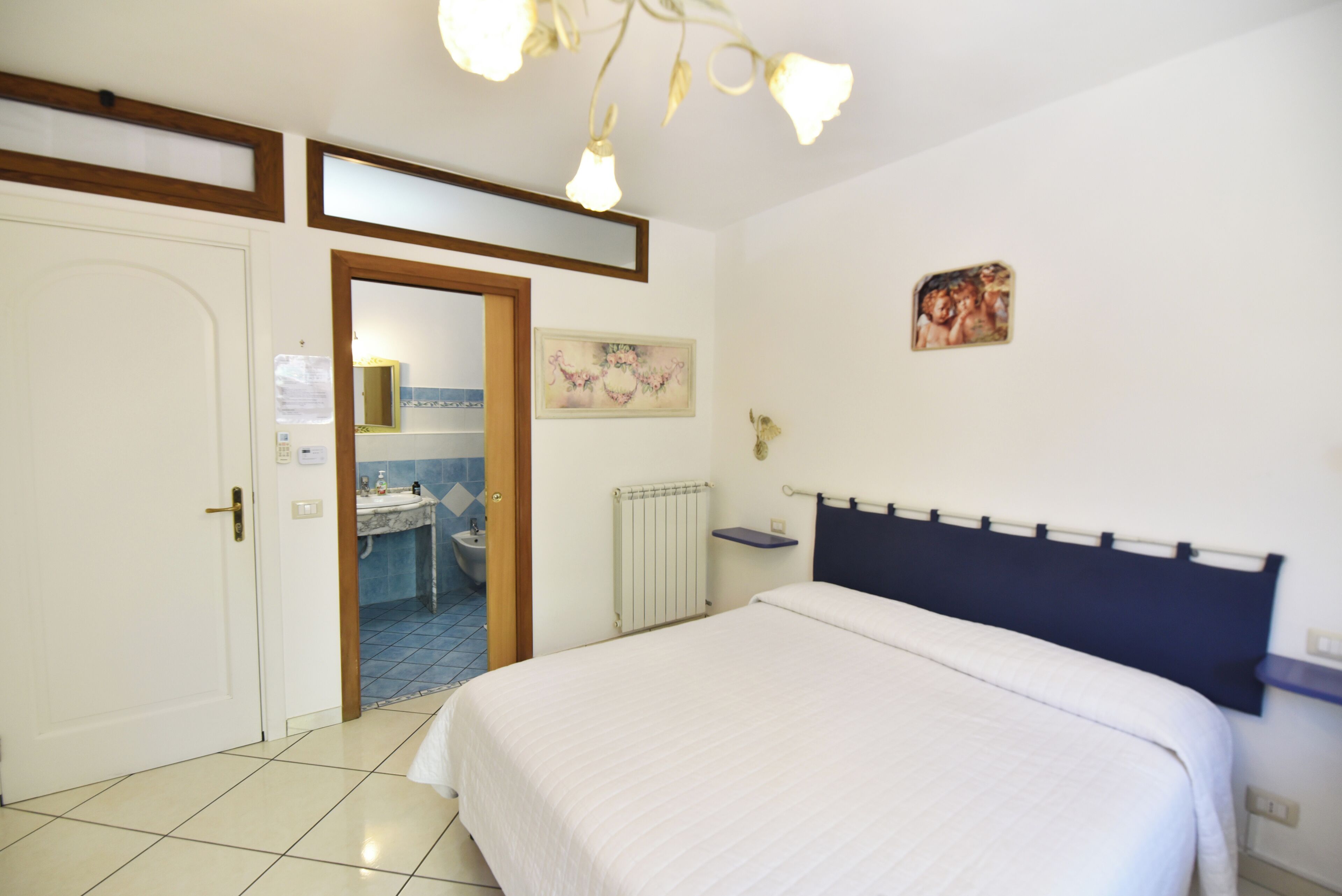 A bedroom with a bed, a bathroom with a sink, and a door leading to another room.