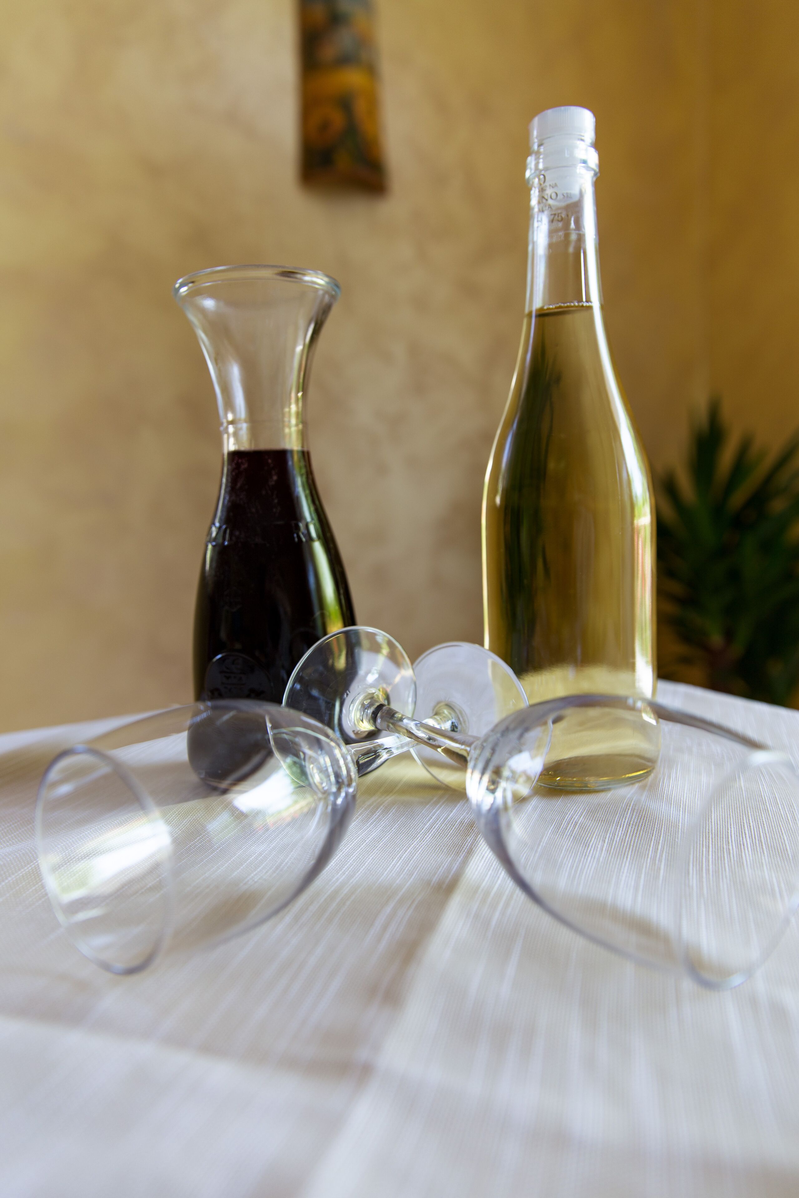 Two wine bottles and several wine glasses on a table.