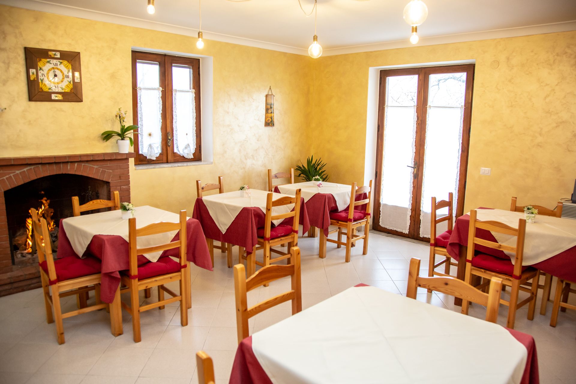 A dining area with wooden tables and chairs, a fireplace, and large windows.