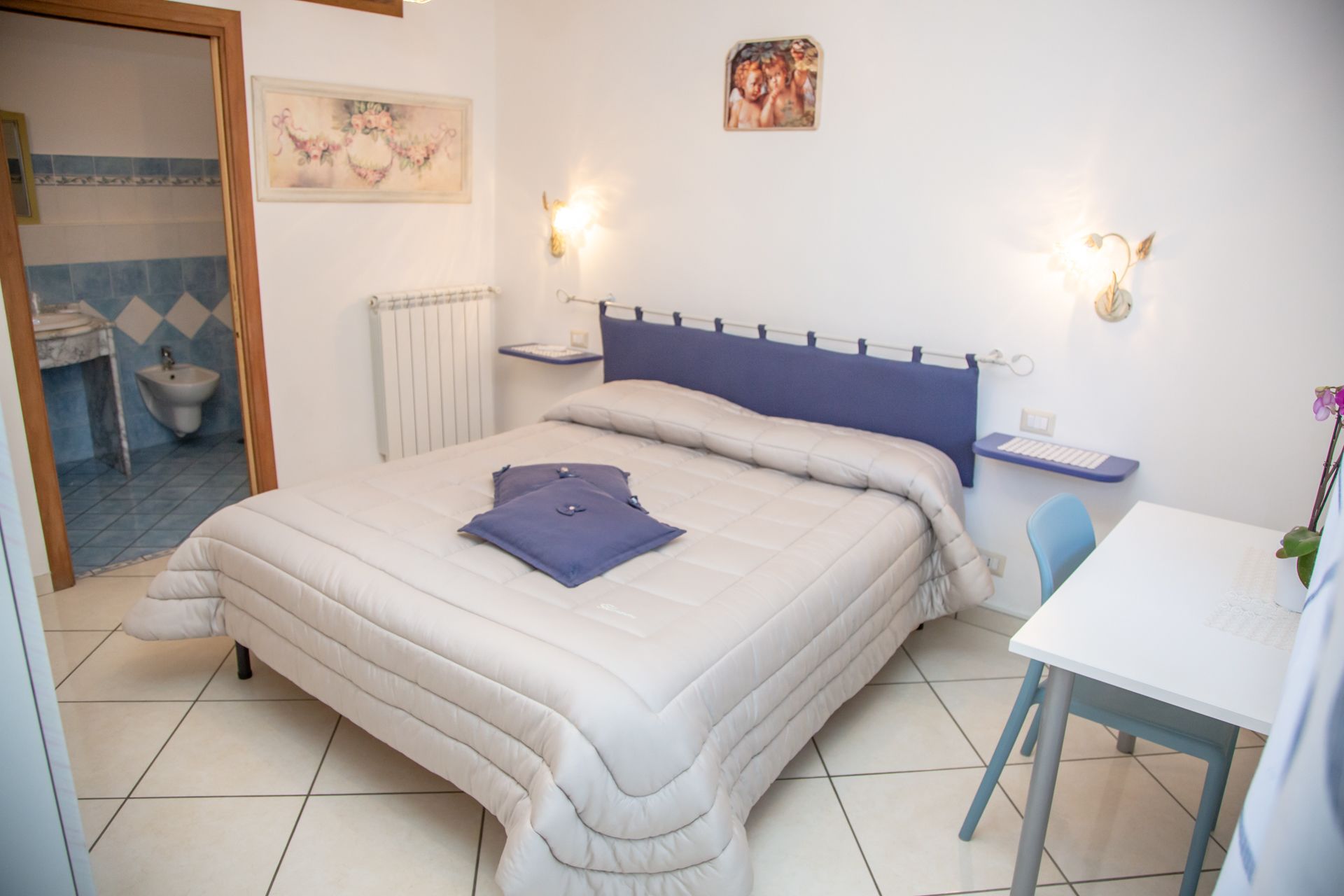 Un dormitorio con cama, mesita de noche y un pequeño escritorio con silla.