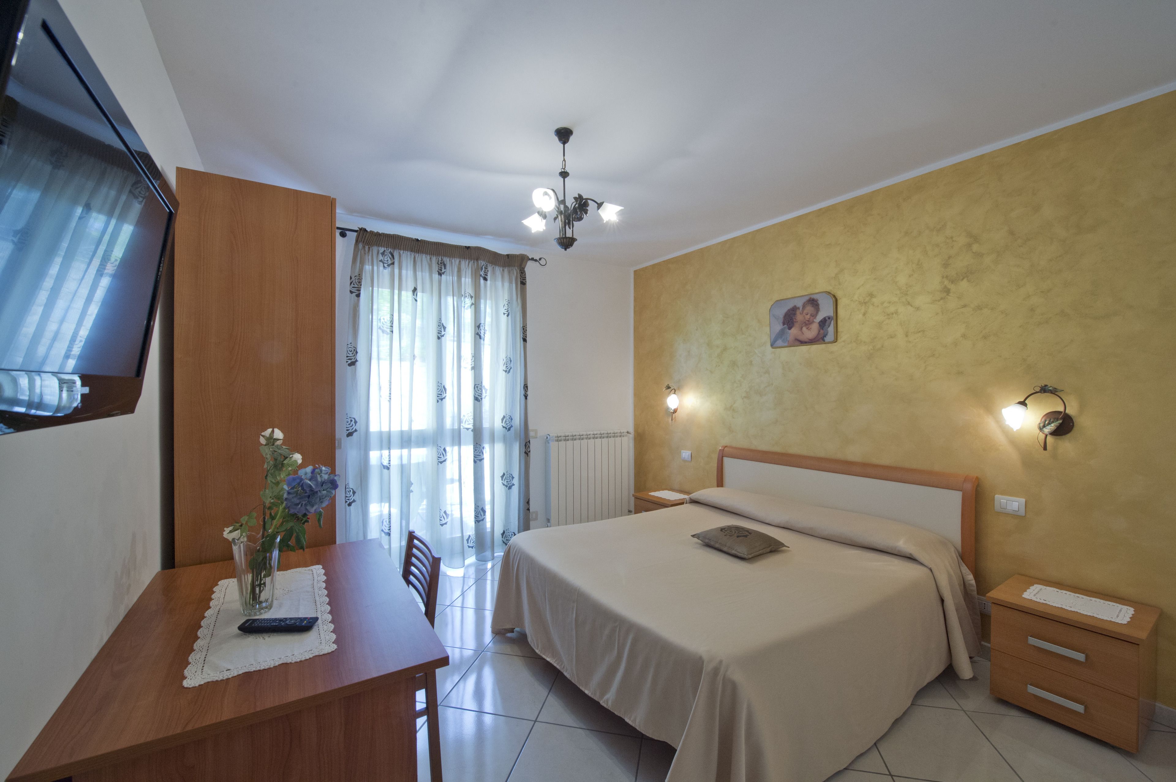 Une chambre à coucher avec un lit, une table de chevet, une lampe et une fenêtre avec des rideaux.