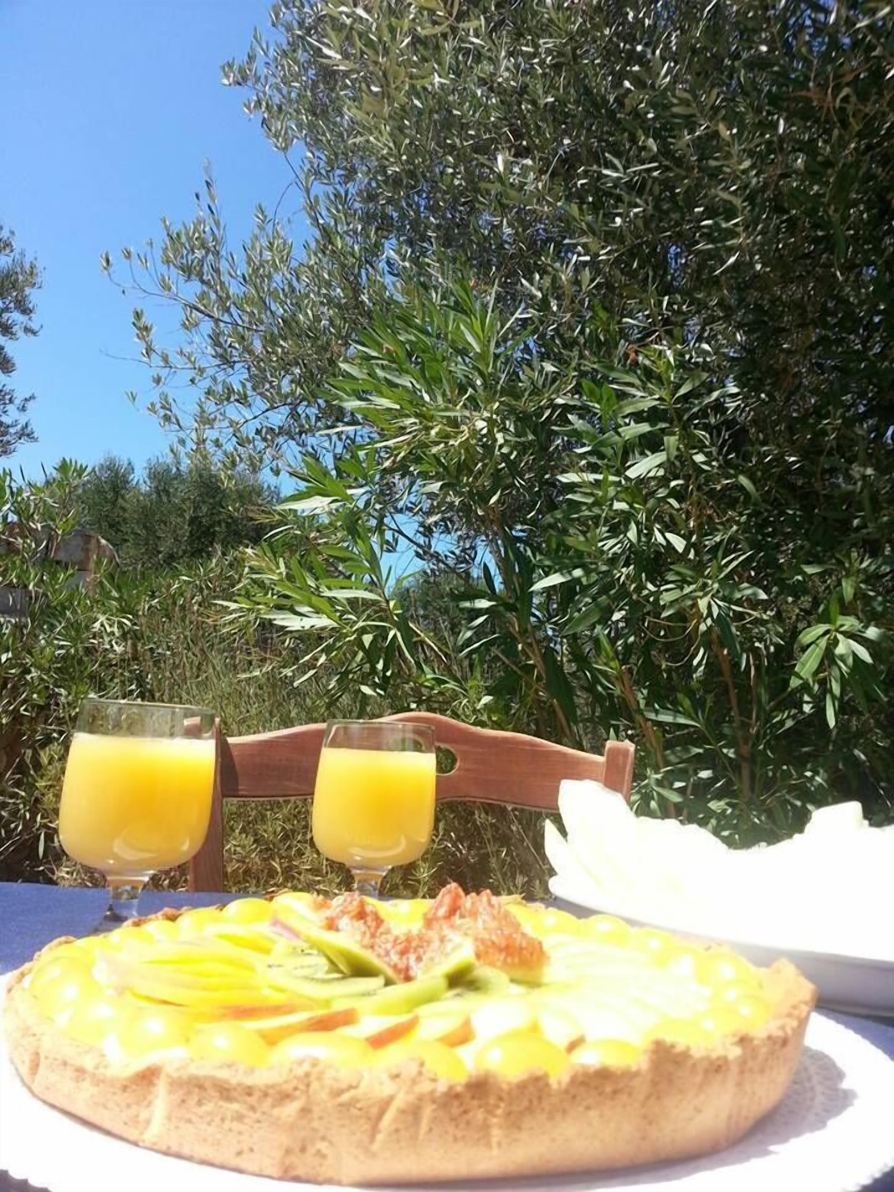 Una mesa con un plato de comida, dos vasos de jugo de naranja y una silla de madera.