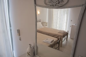 A bedroom with a bed, bedside table, and a mirror reflecting the room. - George House Apartments & Villa (Lefkada)
