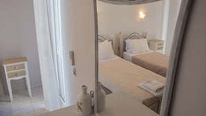 Une chambre avec deux lits, une table de chevet, une commode et un miroir qui reflète la pièce.