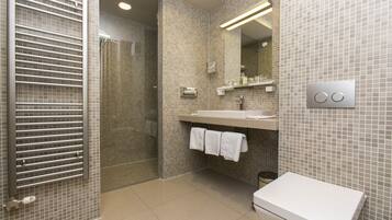 Un baño moderno con cabina de ducha de vidrio, un lavabo blanco y un inodoro.