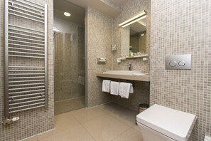 Features a walk-in shower, separate toilet area, and vanity with mirror.