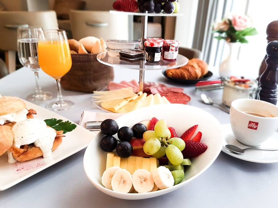 Un bufé de desayuno con diversas opciones de comida, como frutas, quesos y pasteles.