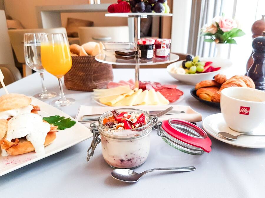 A breakfast setting with various food items, including pastries, cheese, and a glass of orange juice.