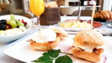 A breakfast setting with sandwiches, a fruit bowl, and a glass of orange juice.