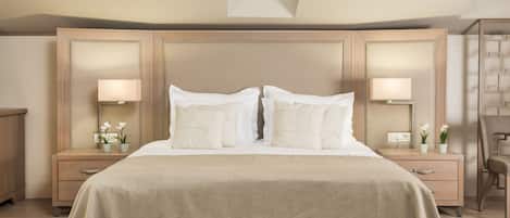 A bedroom with a large bed, two bedside tables, a nightstand, a mirror, and a small potted plant.