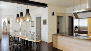 A modern kitchen with a central island, stainless steel appliances, and a dining area with a glass table and metal chairs.