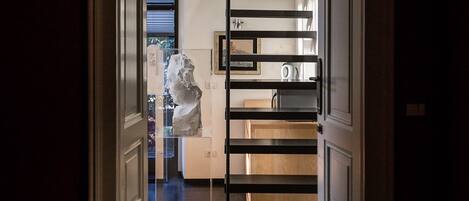 A modern interior with a staircase leading to a second floor, a kitchen area with a refrigerator, and a dining table.